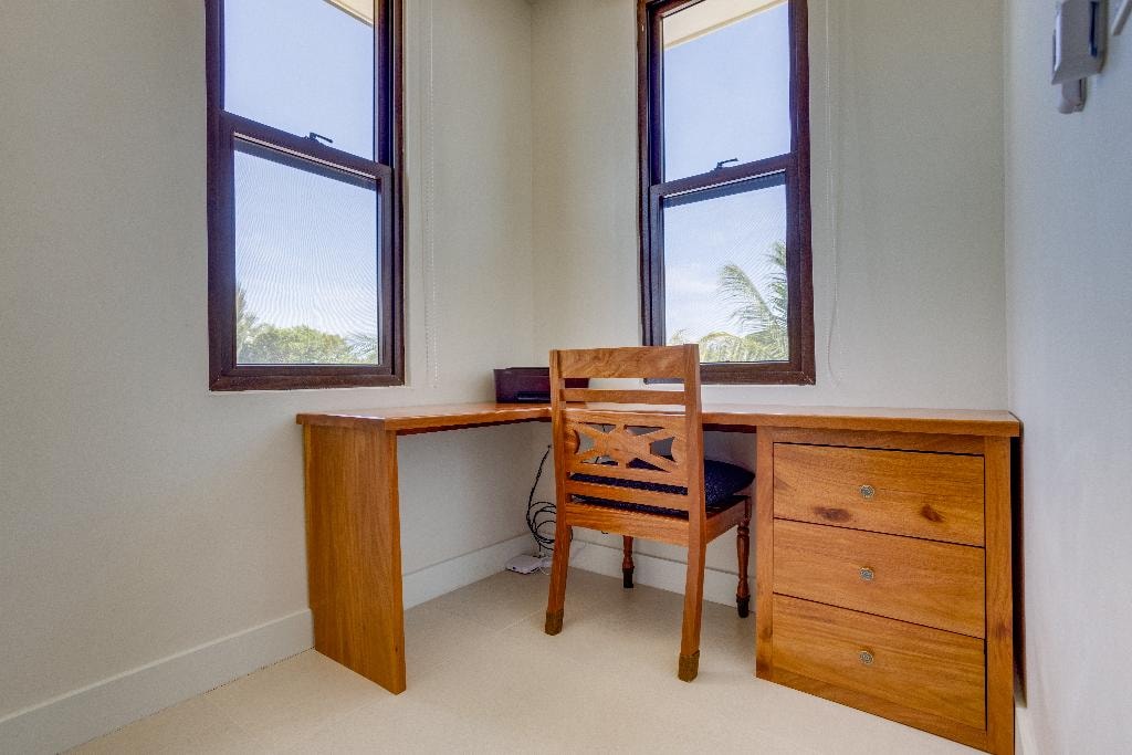 Teak corner desk with drawers and palm views through double windows