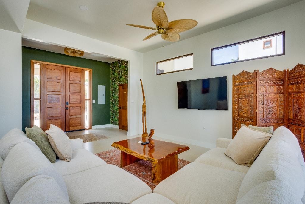 Living room with green accent wall, teak coffee table and ceiling fan