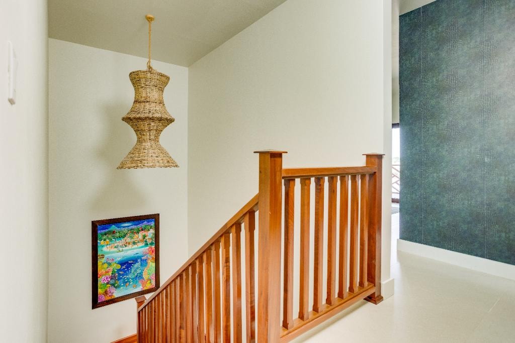 Staircase landing with woven pendant light and Belizean artwork